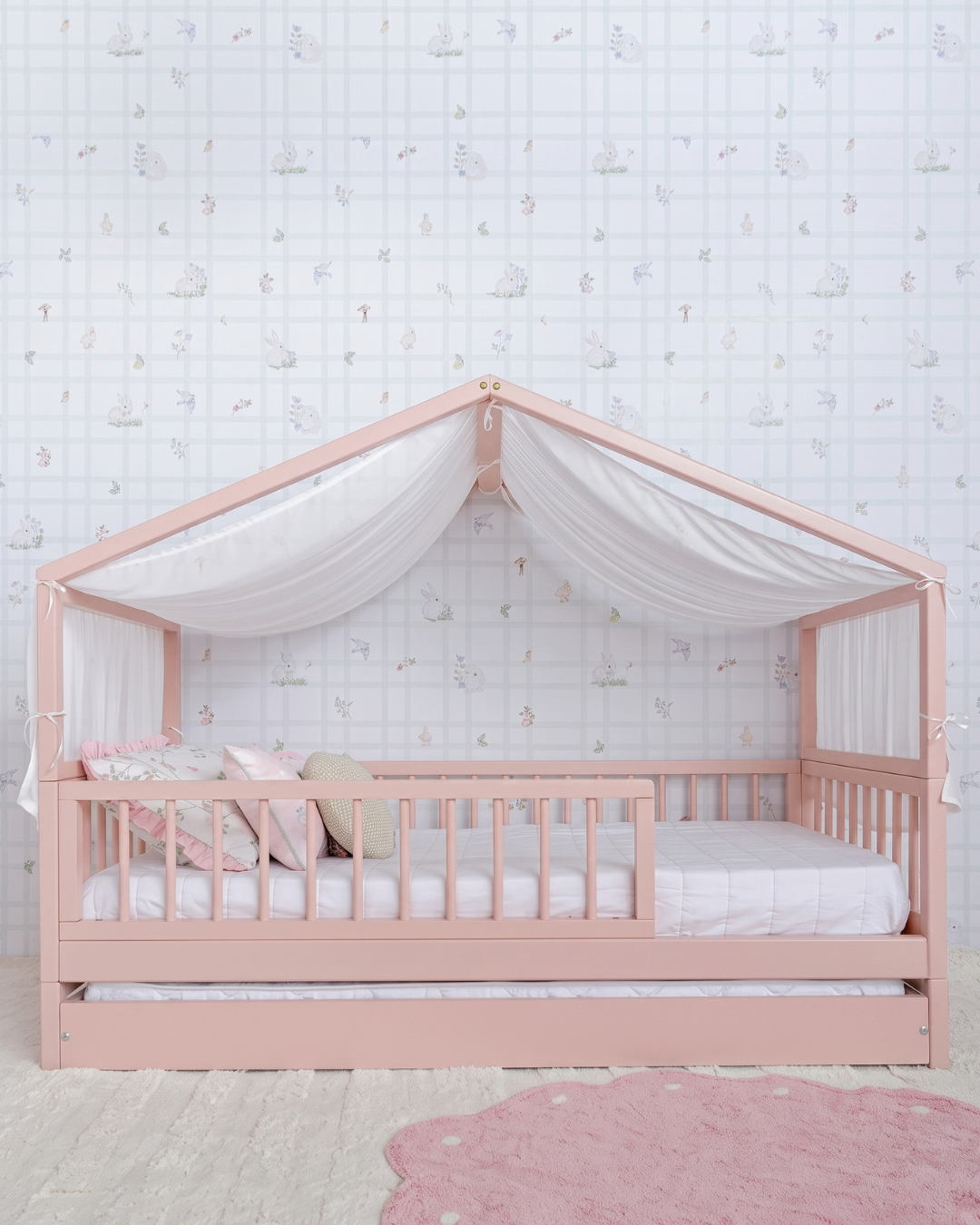 Bicama Casinha Palito 4 em 1 na cor Rosa, com a estrutura de casinha e dossel de tecido, no quarto.