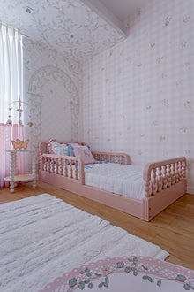 Cama Poema 3 em 1 na cor Rosa, vista frontal no quarto, com cabeceira torneada.