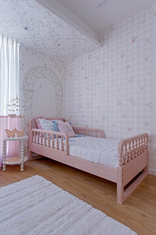 Cama Poema 3 em 1 na cor Rosa, vista em ângulo no quarto, com grade lateral.
