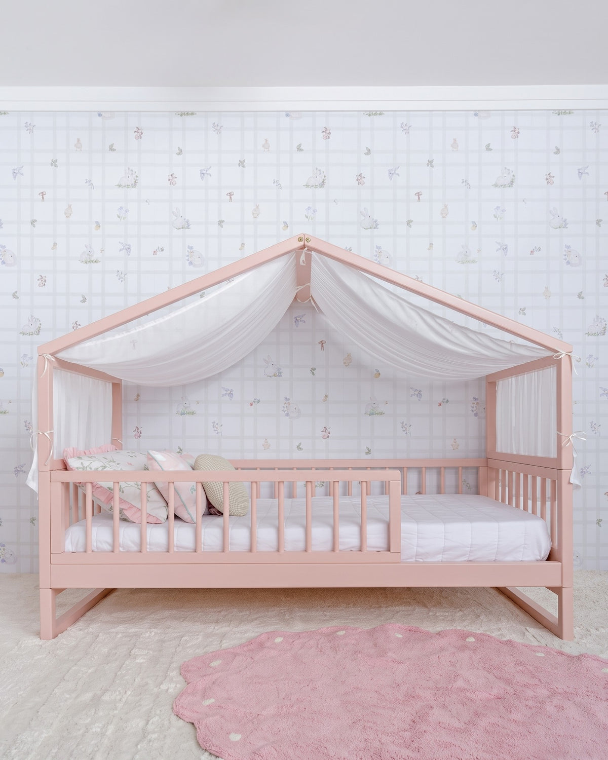 Cama Casinha Palito Evolutiva 4 em 1 na cor Rosa, com a estrutura de casinha e dossel de tecido, vista em ângulo.