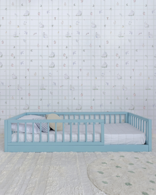 Cama Palito Evolutiva 4 em 1 na cor Azul, vista em ângulo no quarto, com grade lateral.