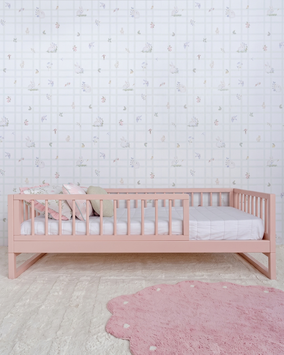 Cama Palito Evolutiva 4 em 1 na cor Rosa, vista em ângulo no quarto, com grade lateral.