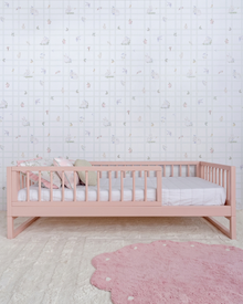 Cama Palito Evolutiva 4 em 1 na cor Rosa, vista em ângulo no quarto, com grade lateral.