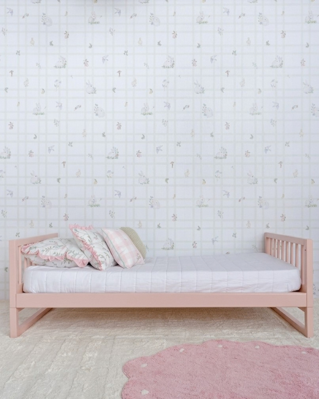 Cama Palito Evolutiva 4 em 1 na cor Rosa, em modo sofá, vista em ângulo no quarto.